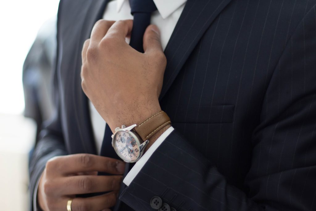 Close-up of person in suit adjusting tie